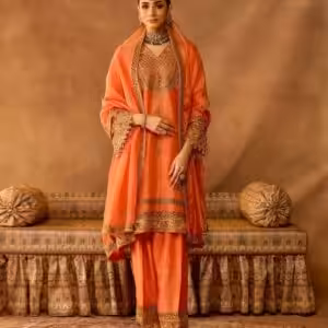 Model wearing peach gold embroidered salwar suit with matching dupatta and traditional jewelry