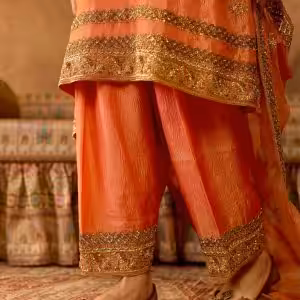 Closeup of embroidered borders and ankle of peach gold salwar suit set