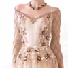 Close-up of champagne evening gown with intricate gold embroidery and maroon floral accents